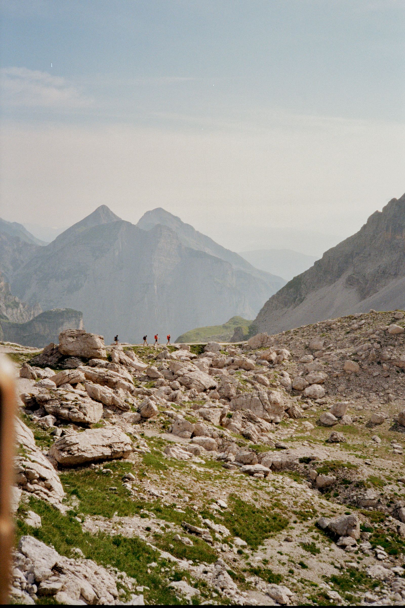 Una pietraia che scende verso una valle, con cime lontane nella foschia